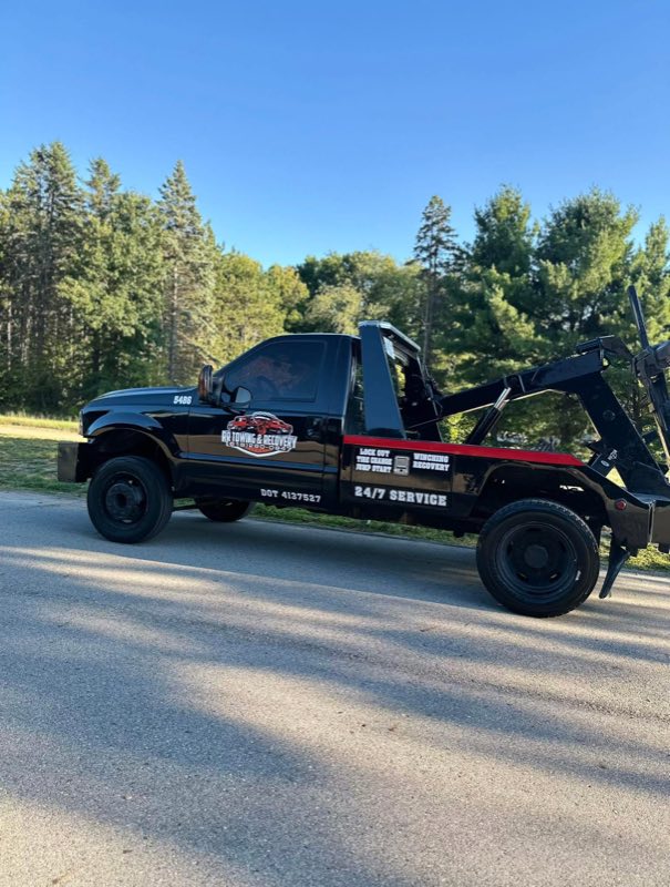RR Towing & Recovery black wheel-lift tow truck lettered 24/7 Service, parked on a country road